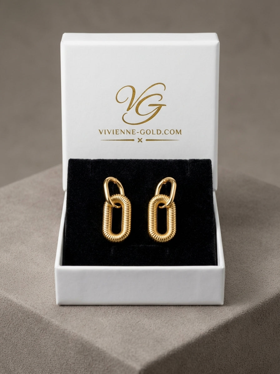 A pair of gold chain-link hoop earrings displayed in an open white jewelry box with a black velvet insert. The inside lid of the box shows the gold logo and text 'VIVIENNE-GOLD.