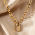A gold chain necklace featuring a small padlock pendant encrusted with clear rhinestones, shown against a plain white background.