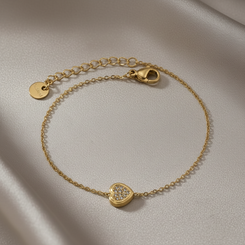 Gold bracelet with a heart-shaped charm on a light background