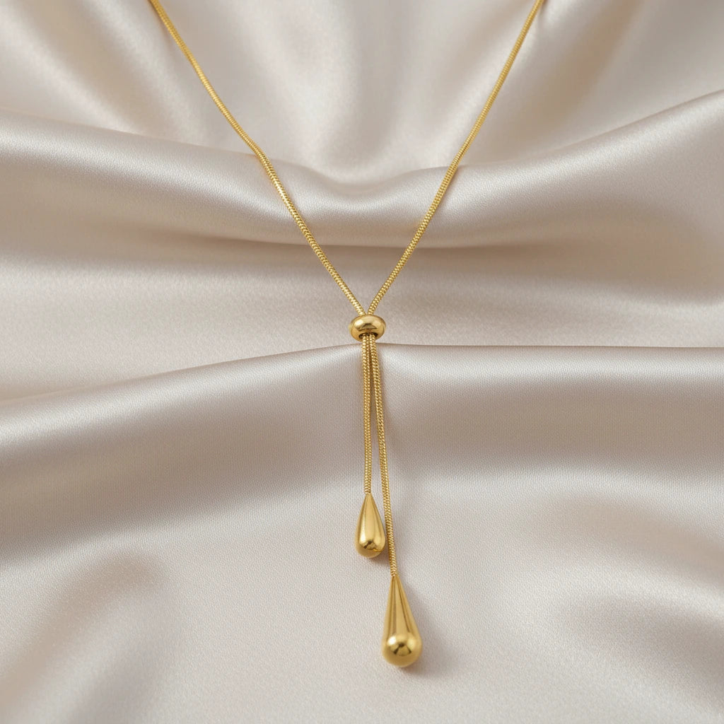 Gold necklace with teardrop pendants on a white background